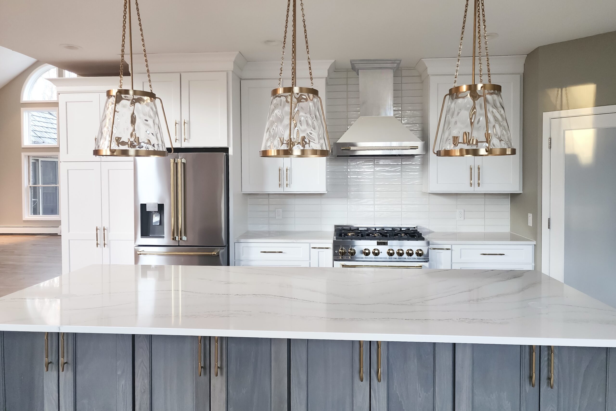 Kitchen with white cabinetry, white marble countertops, and contemporary copper hardware